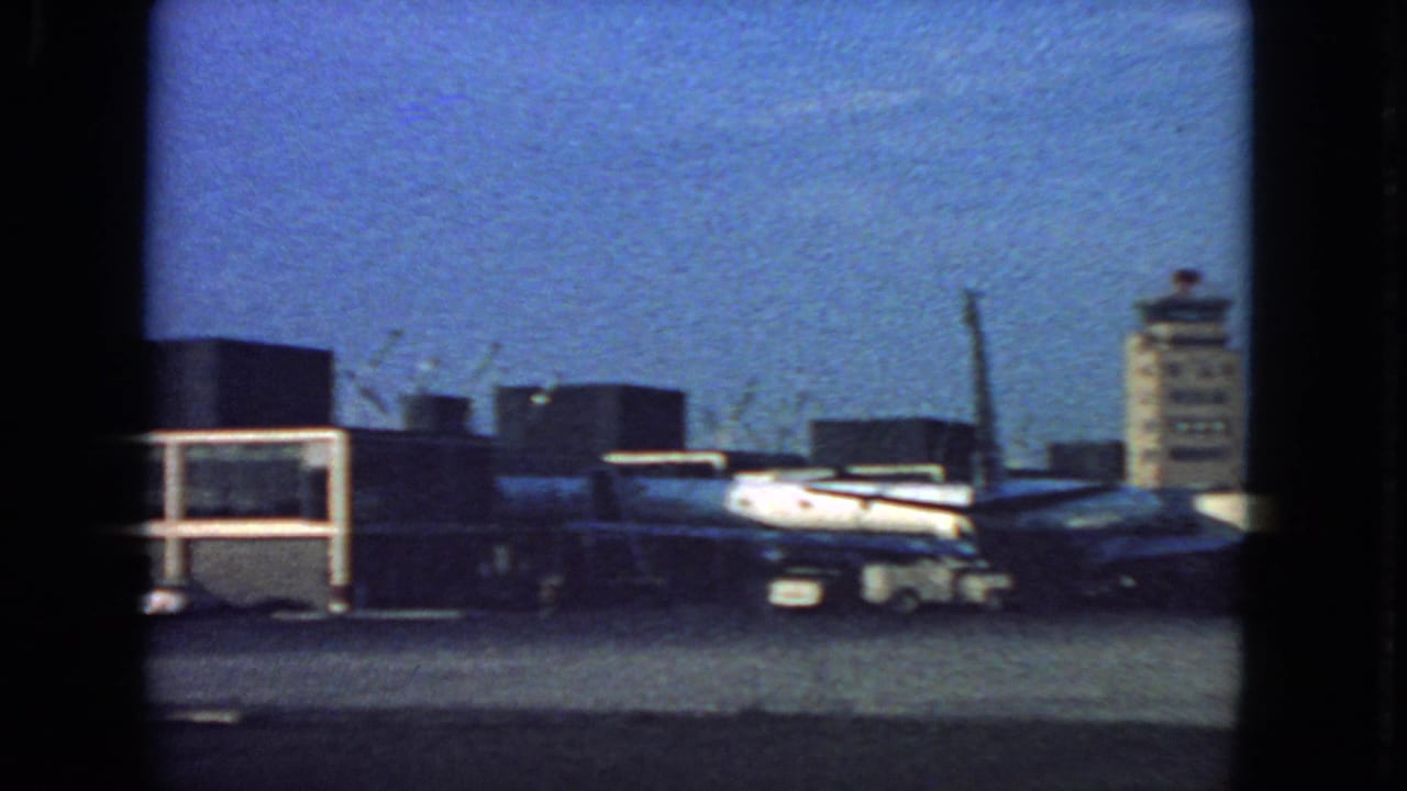 1963 San Francisco airport ramp scene with a parked jet, terminal structures, and control tower in the distance.