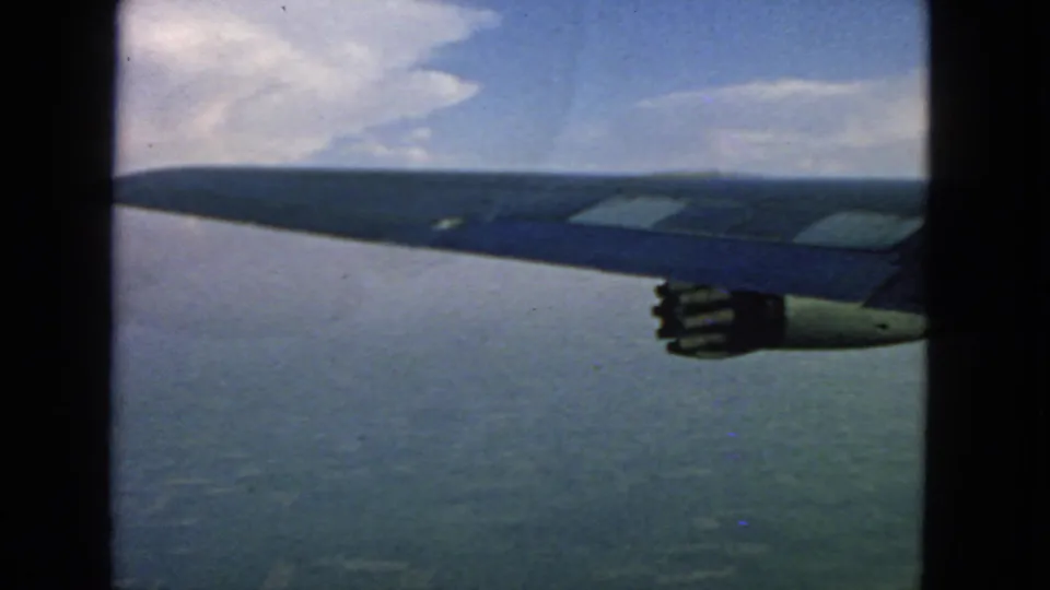 1963 home-movie frame from a passenger plane, showing the wing and engine over a broad water or bay area near San Francisco.