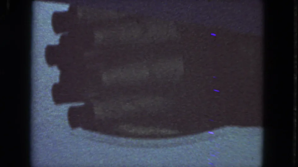 1963 8mm passenger-window view of a blurred airplane engine silhouette against pale sky and film grain.