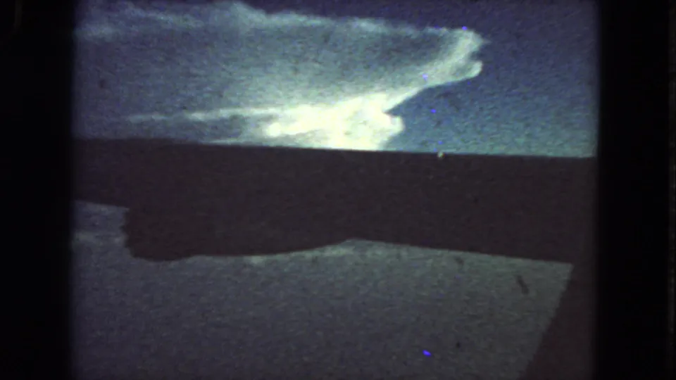 1963 8mm San Francisco home-movie frame showing bright reflected light on water or a reflective surface with dark bands and grain.
