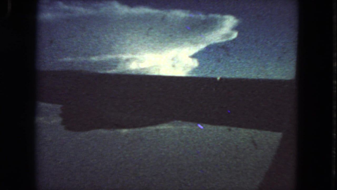 1963 color 8mm frame from San Francisco metadata showing a bright billowing cloud above a dark horizon under blue sky.