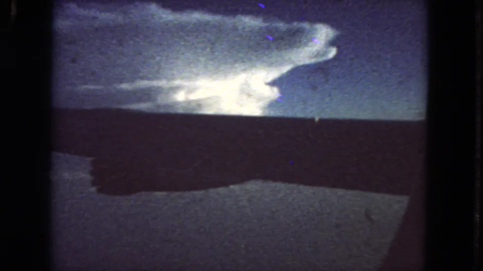 Final 8mm frame shows the billowing cloud shifted slightly above a dark horizon, with blue sky and archival film texture.
