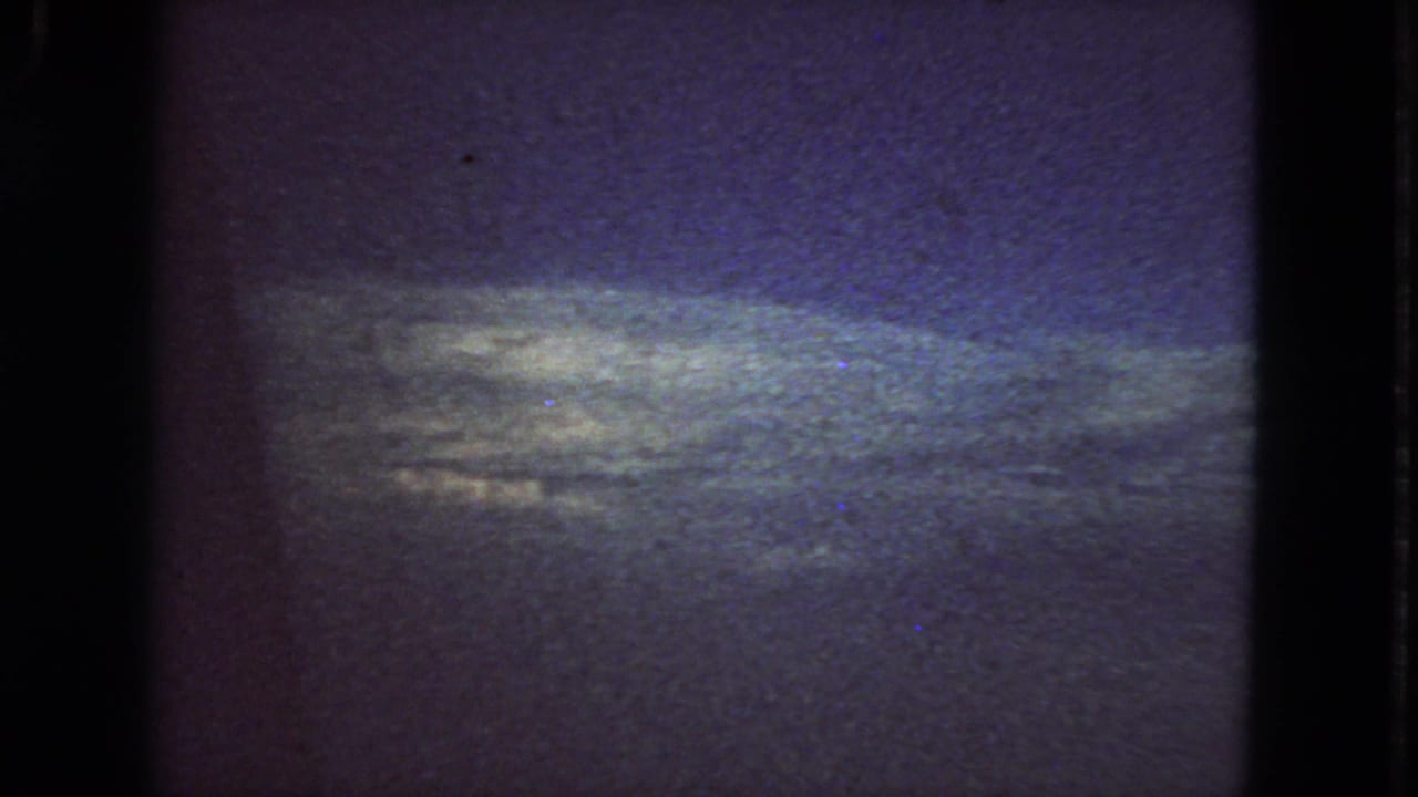 Dark grainy sky above a dim horizon with black 8mm frame edges.