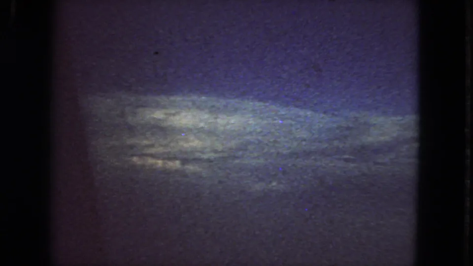 1963 San Francisco 8mm frame showing a dark blue-purple sky and faint horizon band, with heavy grain and visible film gate edges.