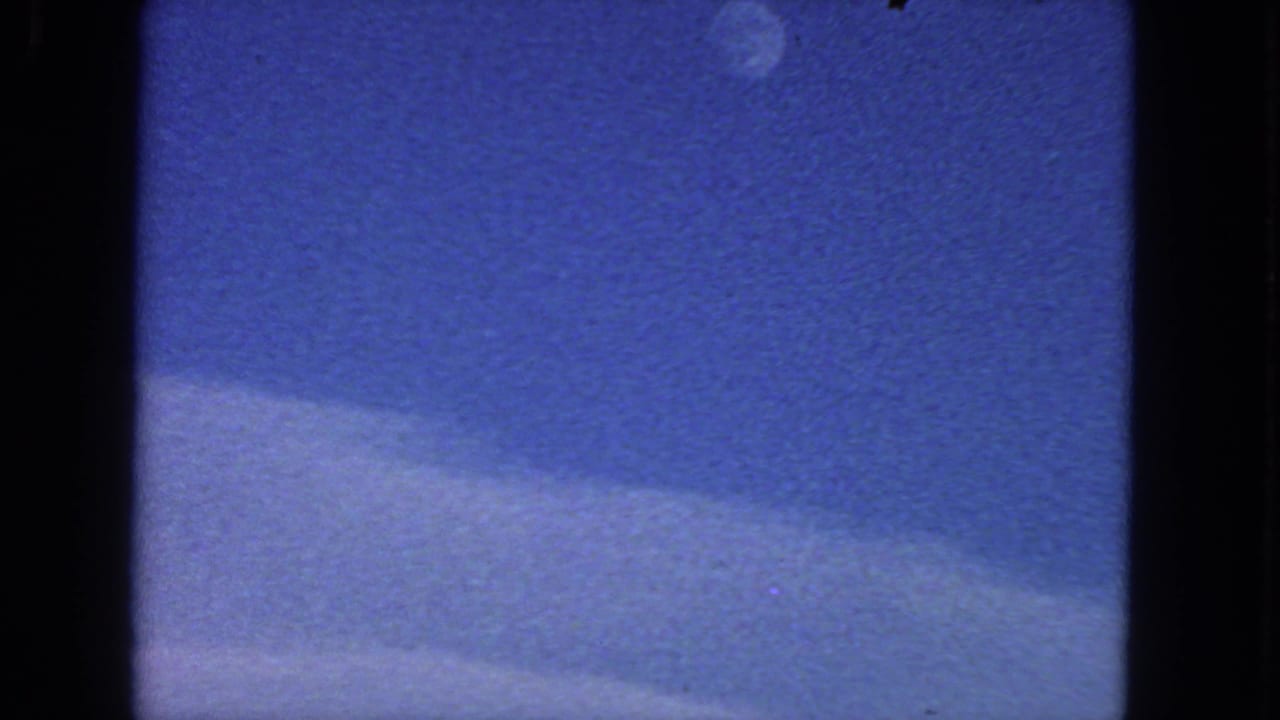 Blue daytime sky with a small moon near the top and pale clouds along the lower edge.