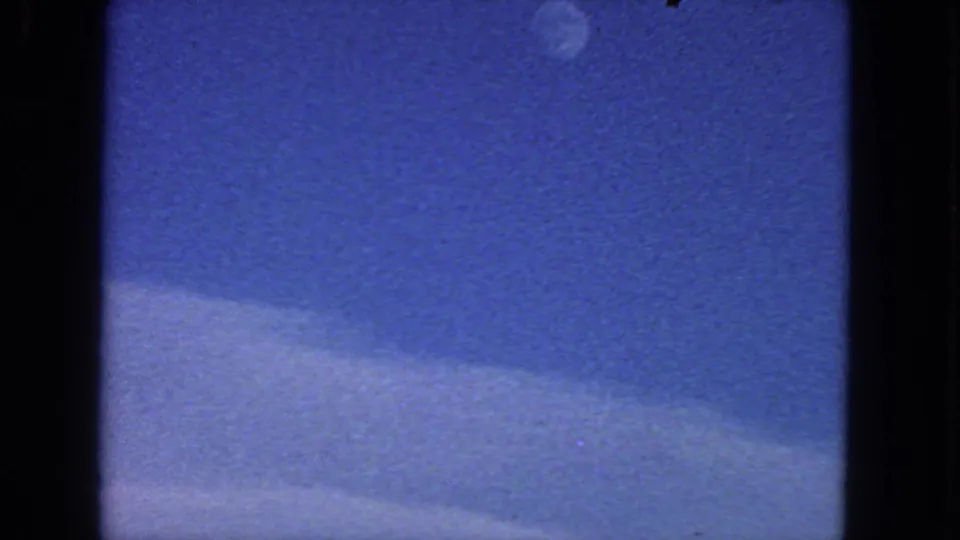 1963 San Francisco-area 8mm frame showing blue sky, a small moon, soft cloud cover, and dark film-gate edges.
