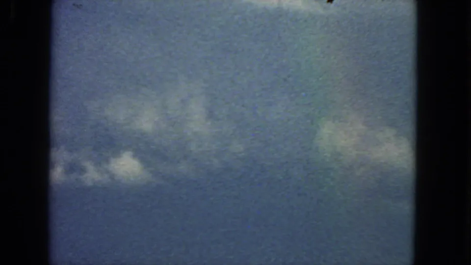 1963 San Francisco-area 8mm frame showing soft clouds against a blue-green sky with visible grain and film-gate edges.
