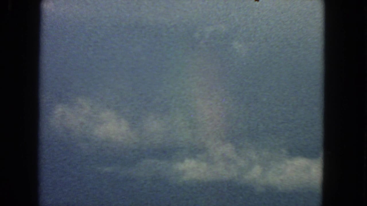 Cloud band against blue sky with dark 8mm frame edges and visible grain.