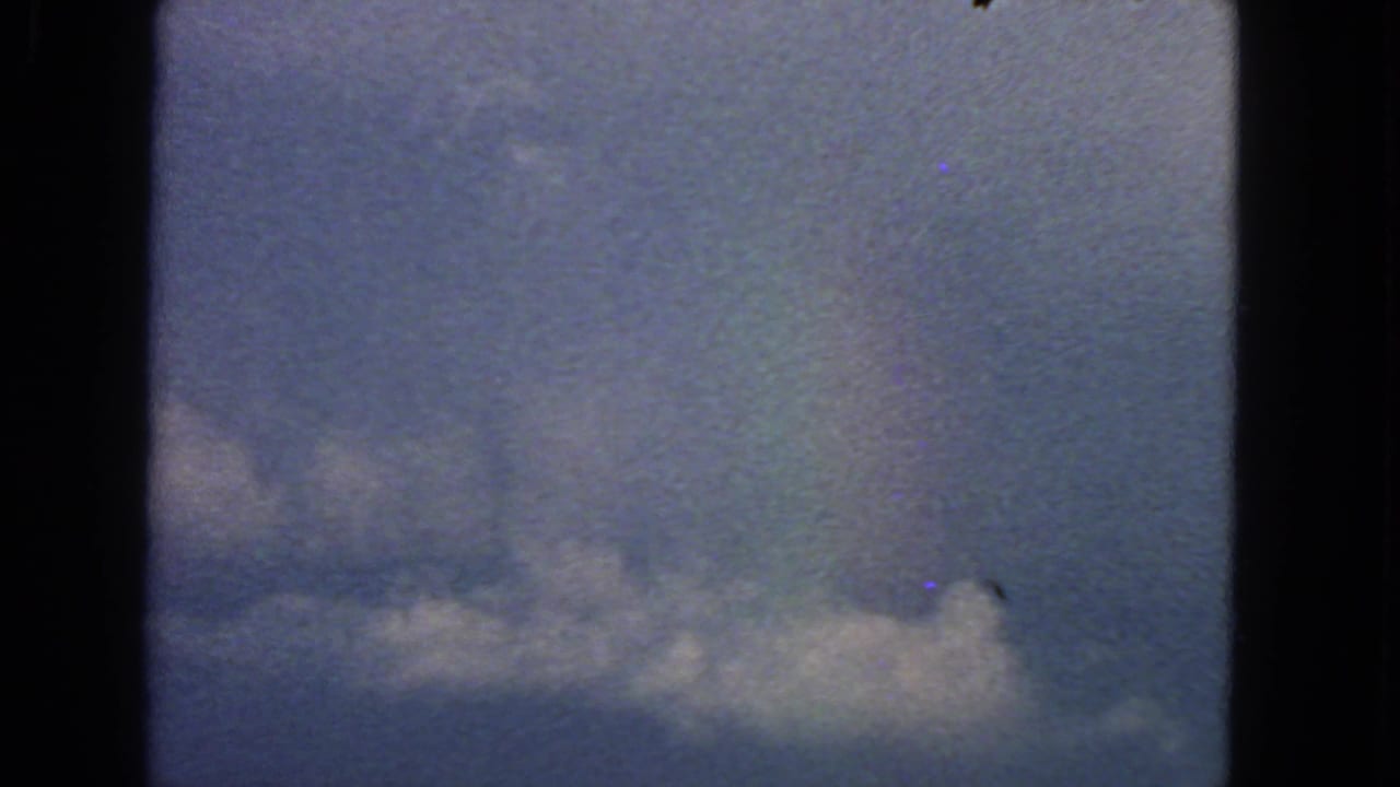 Cloud band against blue sky with dark vertical borders from the filmed window or frame.