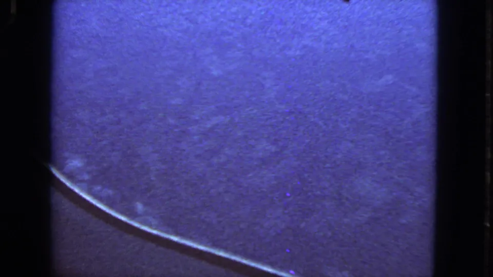 1963 8mm airplane-window view with blue cloudlike texture, visible grain, and dark film-edge framing.