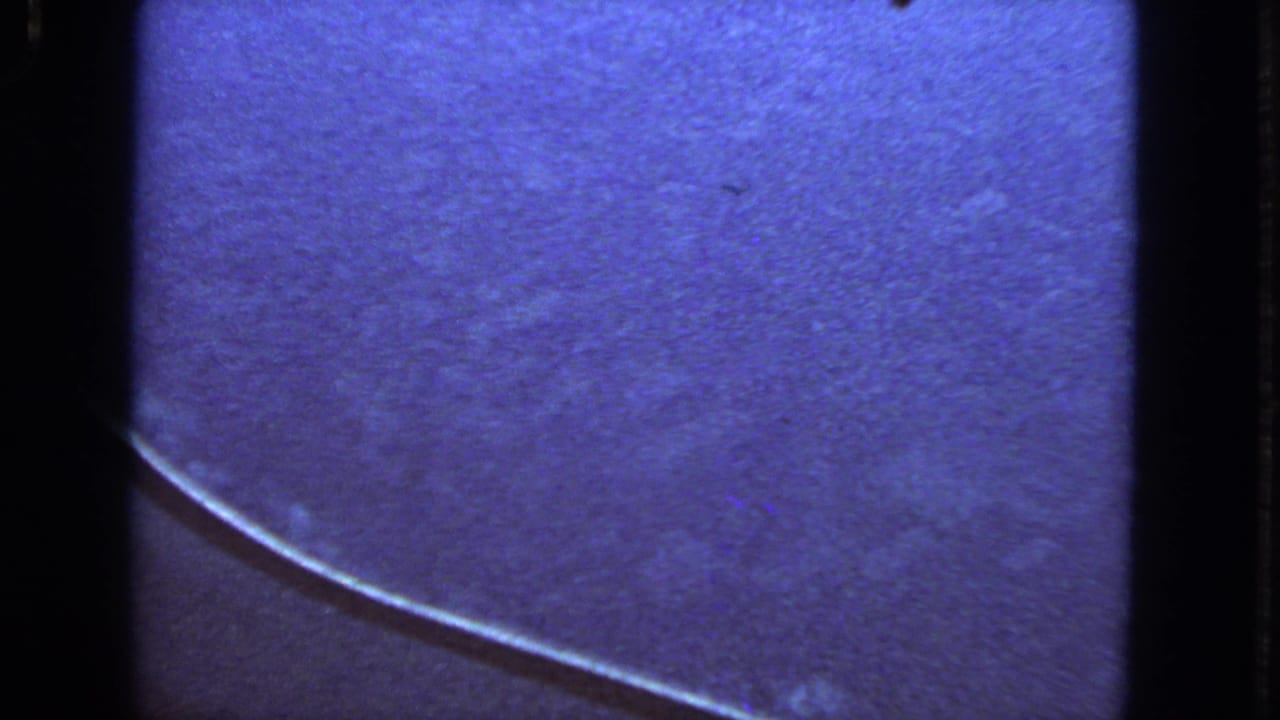 1963 8mm San Francisco travel footage showing a blue-tinted airplane window view with a wing edge and visible film borders.