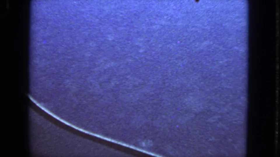1963 8mm airplane-window footage with a curved wing edge, blue sky, grain, and dark gate borders.