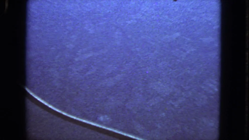 Blue-shifted 1963 8mm airplane-window view with the wing edge cutting across a textured sky field.
