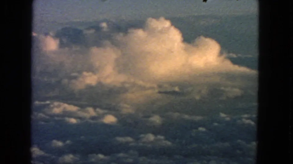 The closing frame shows golden cumulus clouds through a dark airplane-window border in 1963 8mm footage.