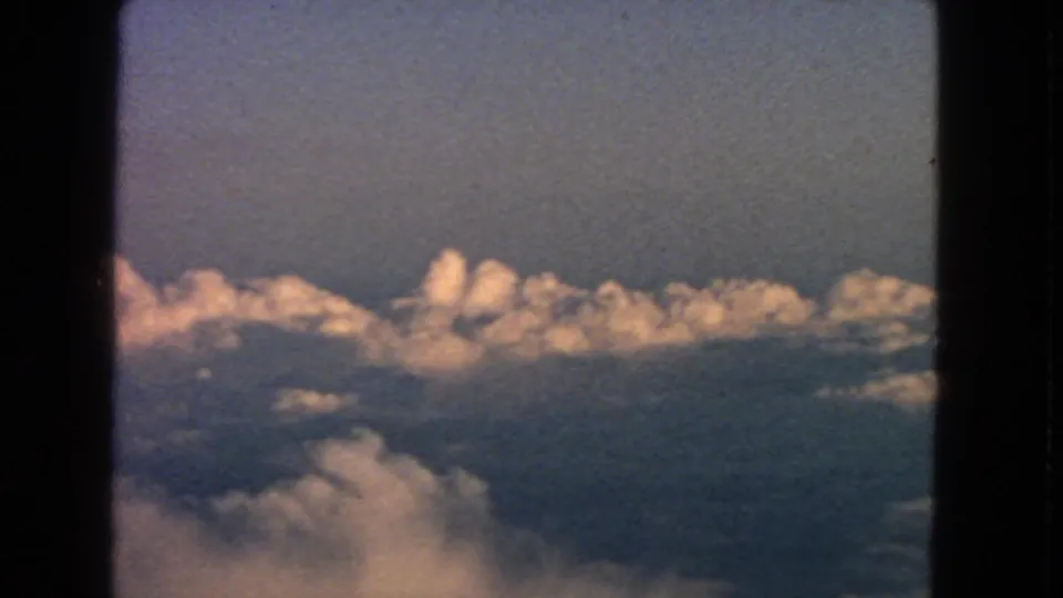 1963 travel footage frame showing a broad cloud layer from an airplane-window perspective.
