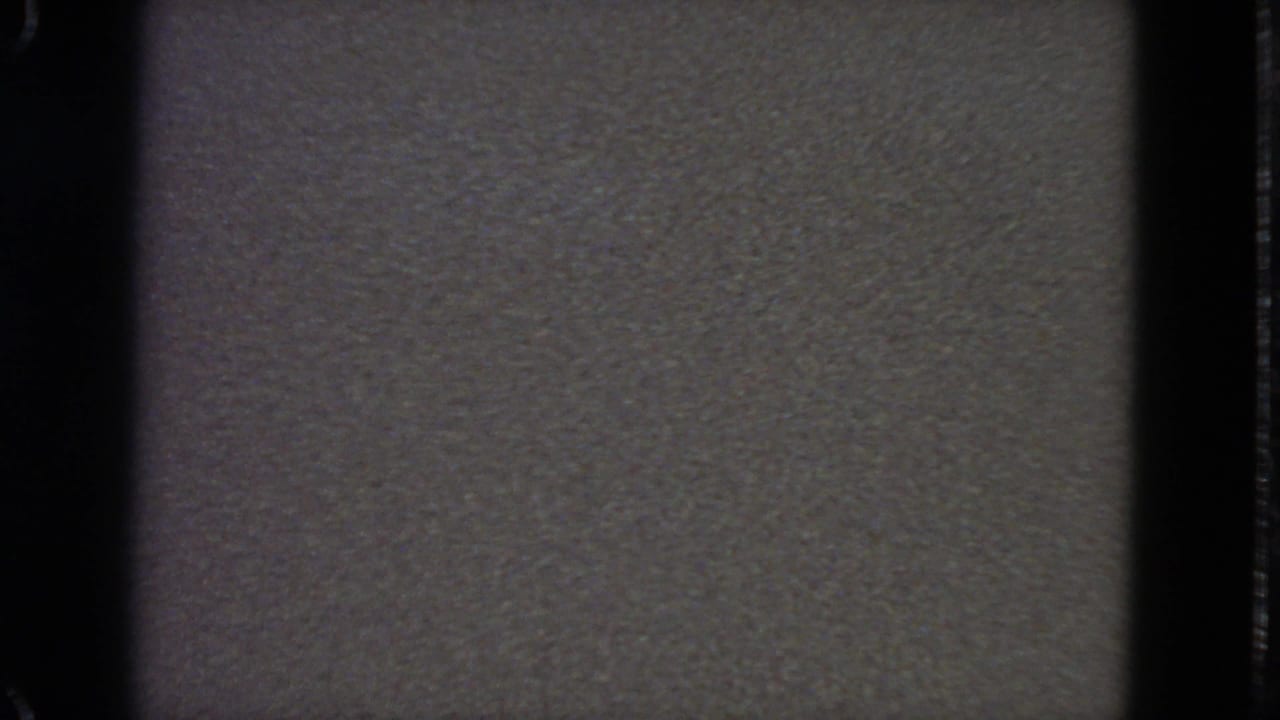 Gray textured field framed by black vertical film borders and a faint center band.