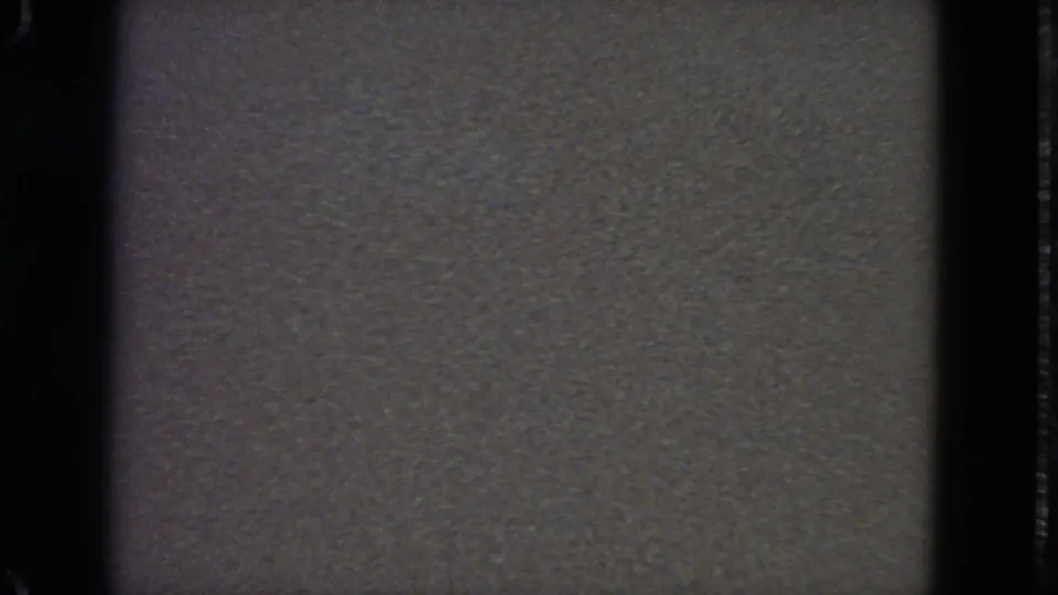 1963 San Francisco home-movie frame with gray screen texture, heavy grain, and dark 8mm border shadows.