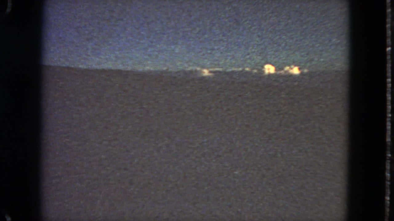 Distant dusk horizon in 1963 San Francisco home-movie footage, with faint orange lights beyond a dark landform.