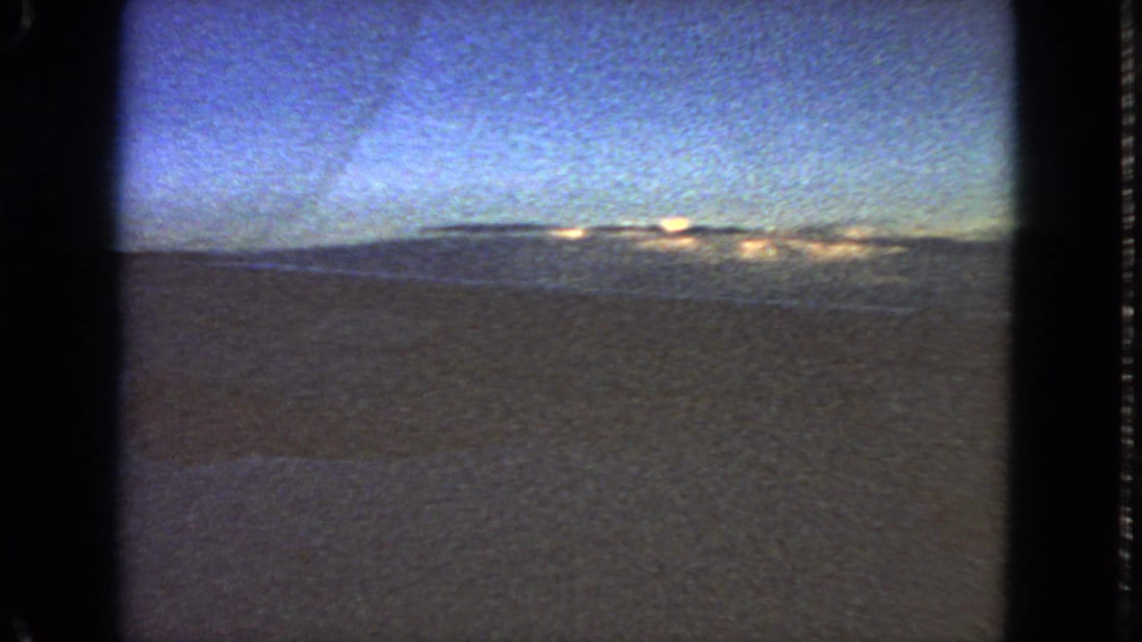 Blue dusk horizon and cloud cover seen through a dark film frame.