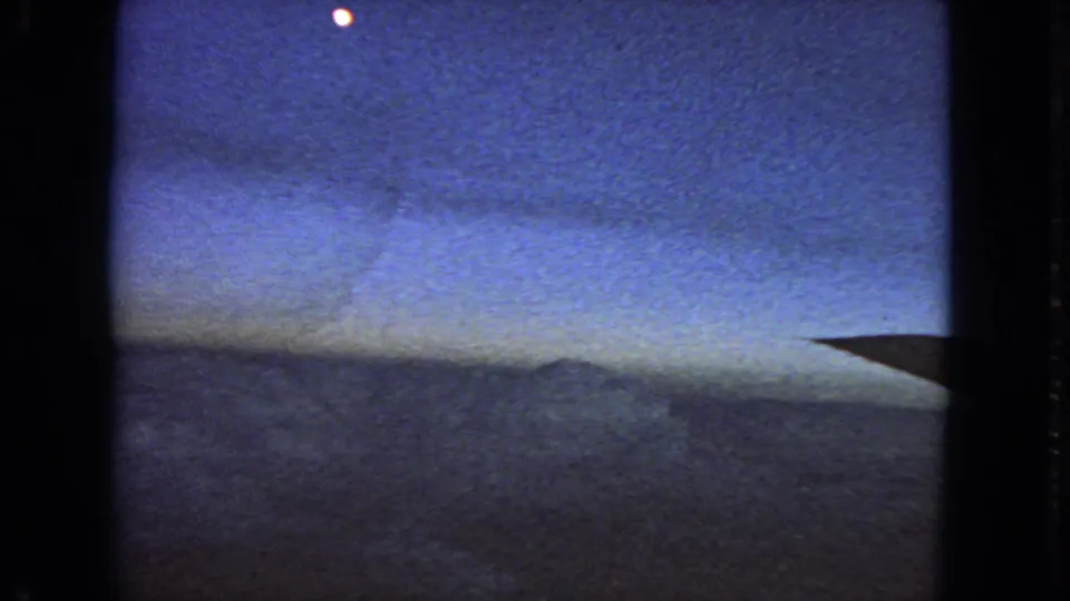 1963 8mm aerial footage near San Francisco showing a cloudy blue horizon and dark aircraft wing edge from inside a plane.