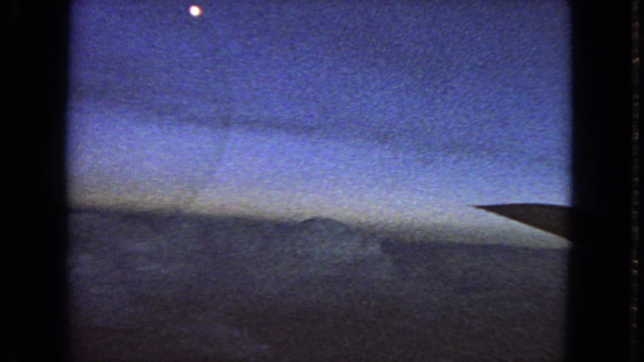 1963 8mm home-movie frame with a blue twilight sky, small bright celestial point, dark horizon, and possible aircraft wing entering from the right.