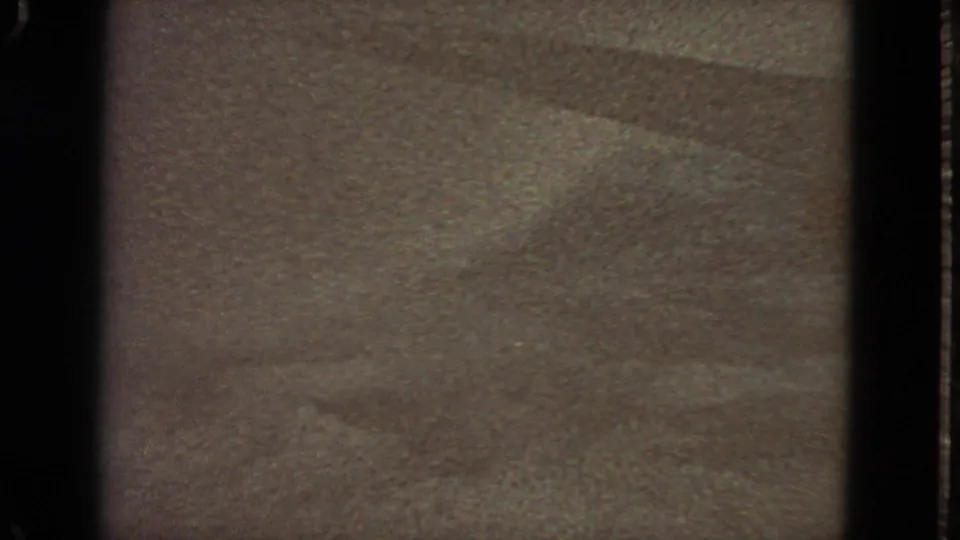 1963 8mm frame from San Francisco metadata showing a soft, grainy surface with faint diagonal shading and dark gate edges.