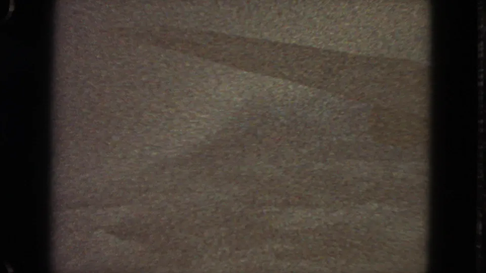 Ambiguous 1963 8mm home-movie frame with a flat textured surface, diagonal tonal bands, and visible film-gate borders.