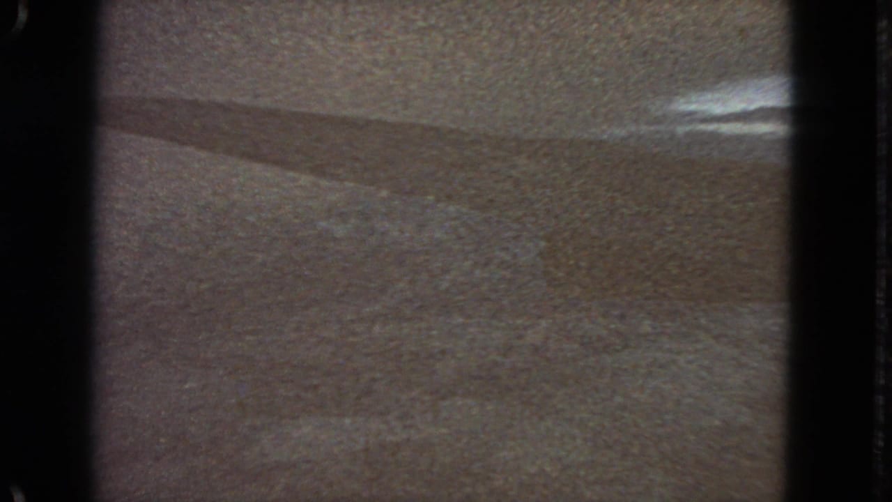 1963 San Francisco-labeled 8mm frame showing a soft, abstract light-toned surface with dark gate edges and a faint diagonal shadow.