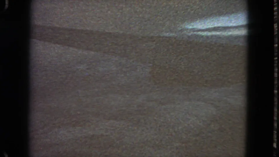 1963 San Francisco-labeled 8mm frame with a grainy surface, dark film edges, and a bright elongated reflection near the upper right.