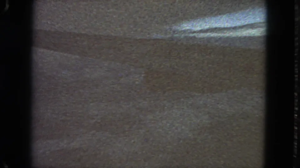 1963 San Francisco-labeled 8mm frame showing a textured surface, dark gate edges, and a bright horizontal streak across the upper right area.