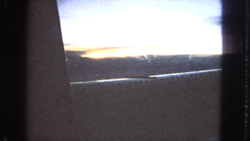 1963 San Francisco 8mm frame showing a glowing sunset horizon through the dark edge of a car window.