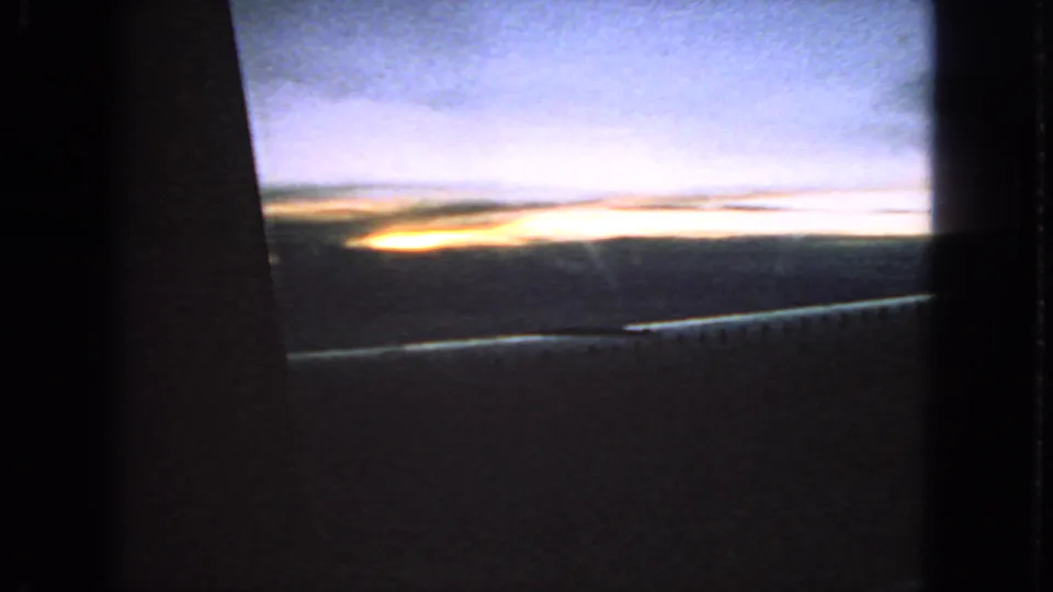 1963 8mm passenger view near San Francisco with sunset light under clouds and a dark car-window frame.