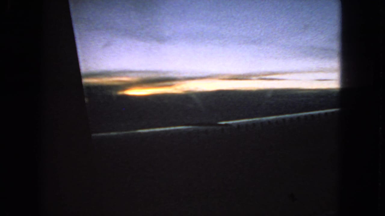 Blue and yellow dawn horizon seen through a dark window opening.