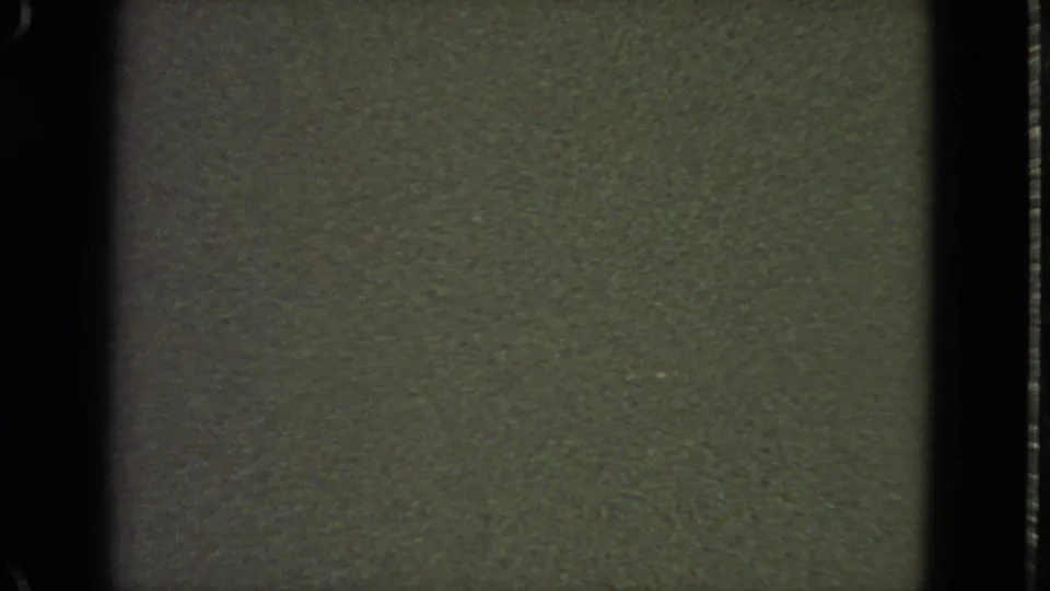 Low-light 1963 8mm San Francisco home-movie frame showing mostly dark olive-gray texture, grain, and film-edge shadows.