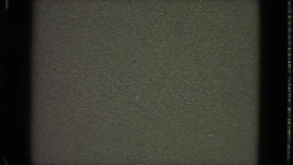1963 8mm San Francisco home-movie frame showing a dim olive-gray field, visible grain, and shadowed film edges.