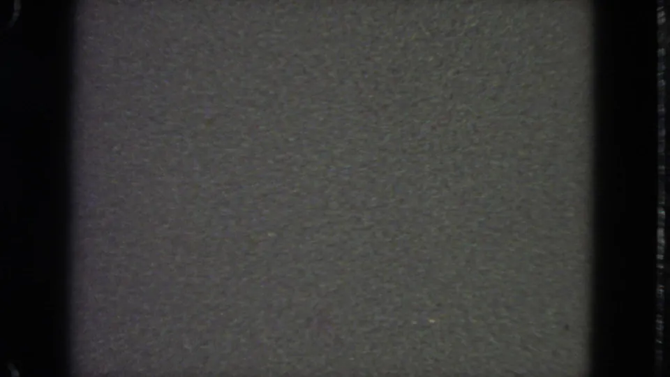 Low-light 1963 San Francisco 8mm frame with muted gray-green texture, heavy grain, and no identifiable figure visible.