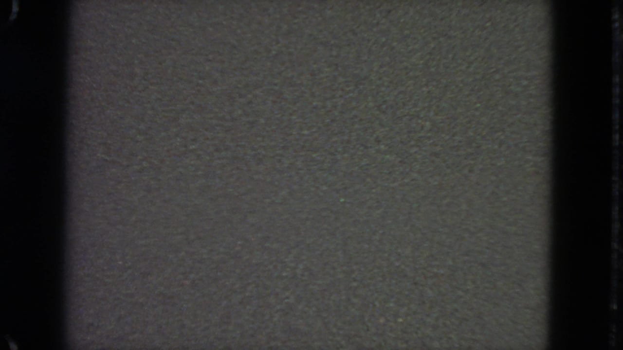 Dark 8mm frame with grain, gate border, and vertical frame edge.