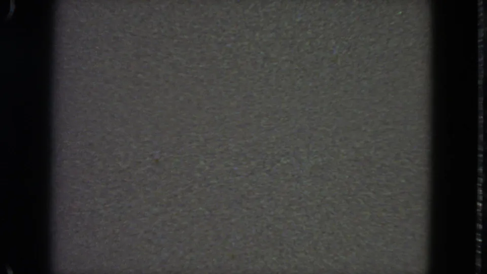1963 8mm frame with a low-contrast gray static field, dark side borders, and subtle film grain across the screen area.