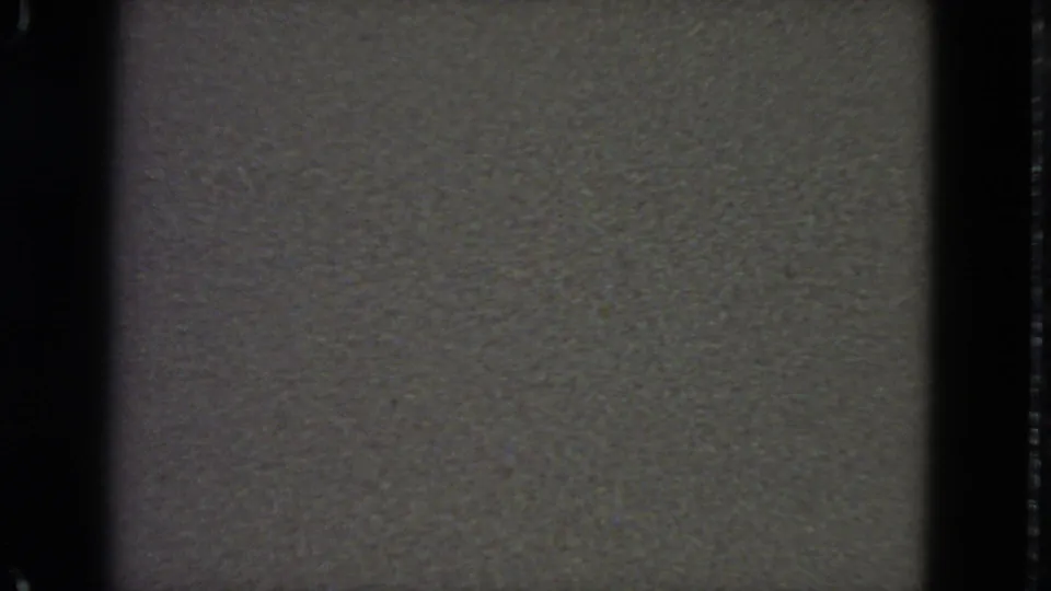 1963 8mm frame with dim gray no-signal static, dark vertical borders, soft exposure, and fine film grain.