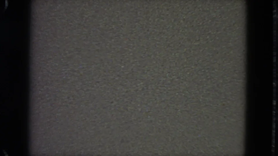 1963 8mm frame showing a blank textured field, dark gate edges, and a subtle darker horizontal band through the center.