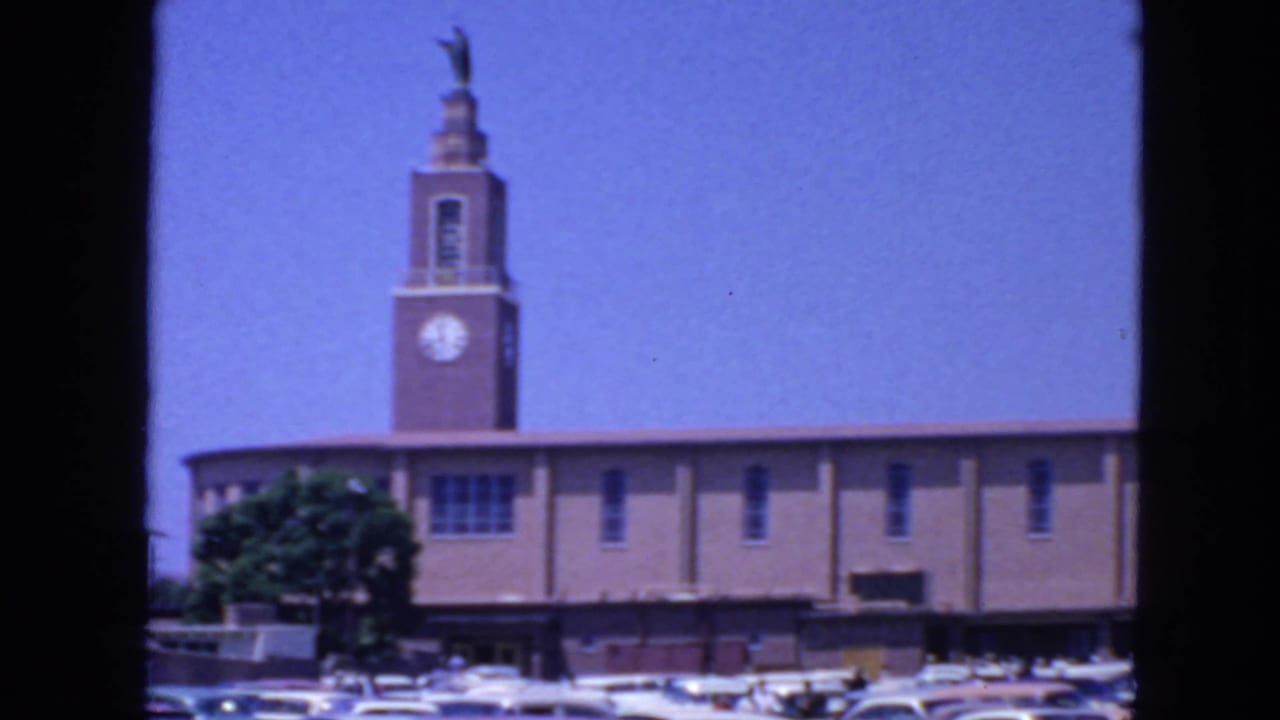 1963 San Francisco frame centered on a brick clock-tower building with parked cars along the lower edge.