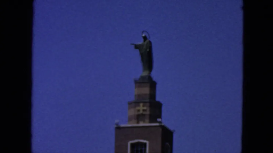 Closer 1963 San Francisco frame isolating the religious statue and upper tower against a clear blue sky.