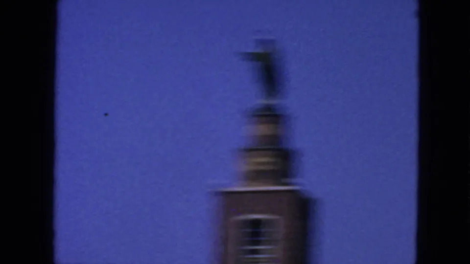 Motion-blurred 1963 San Francisco home-movie frame of the church tower and statue during a handheld camera move.