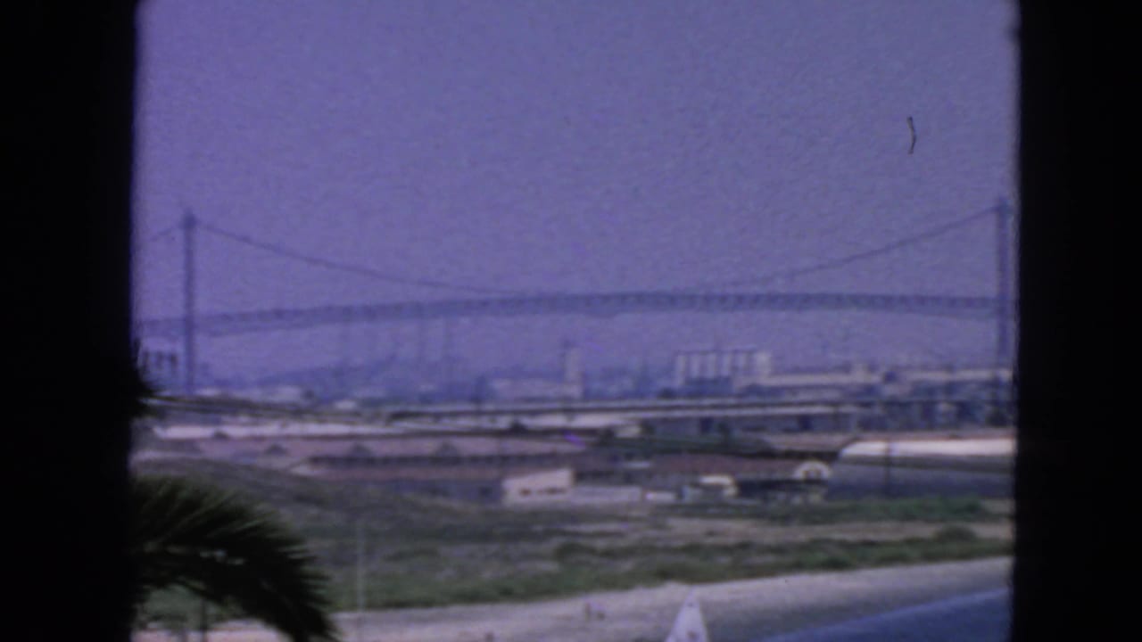 Hazy suspension bridge and waterfront structures framed by dark vertical edges.