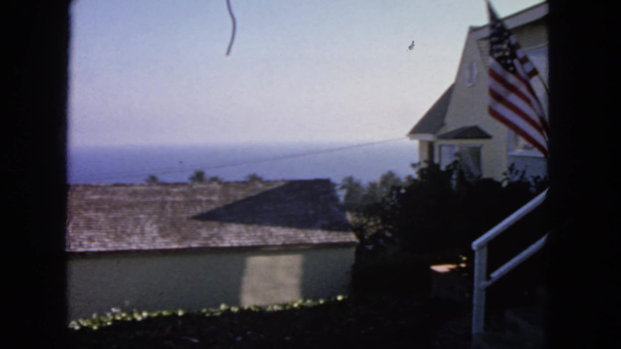 Beige coastal buildings with an American flag and ocean horizon beyond.