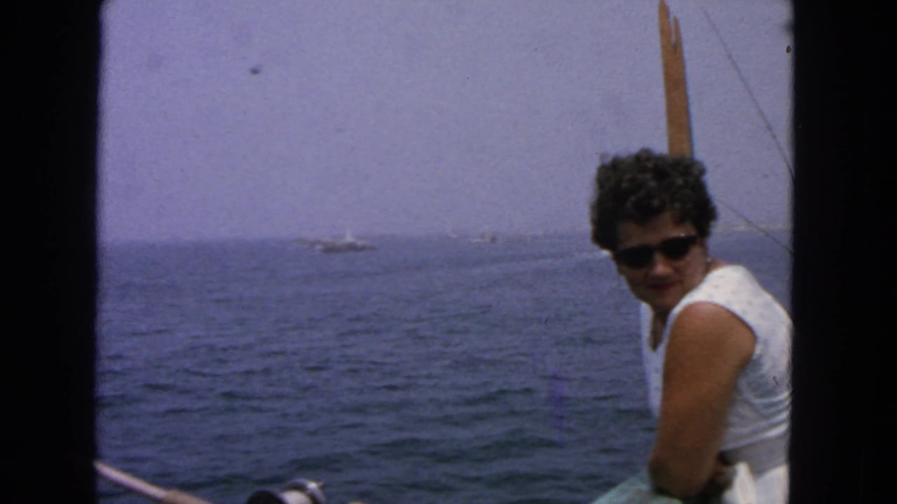 Woman in sunglasses seated on a boat with open ocean behind her.