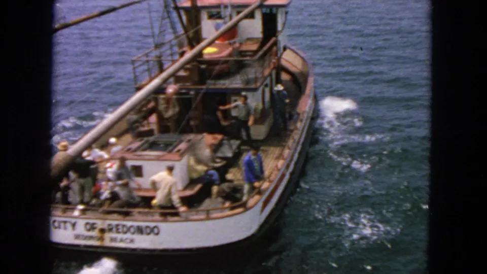 The stern of the fishing vessel CITY OF REDONDO passes through open water with several people visible on deck.