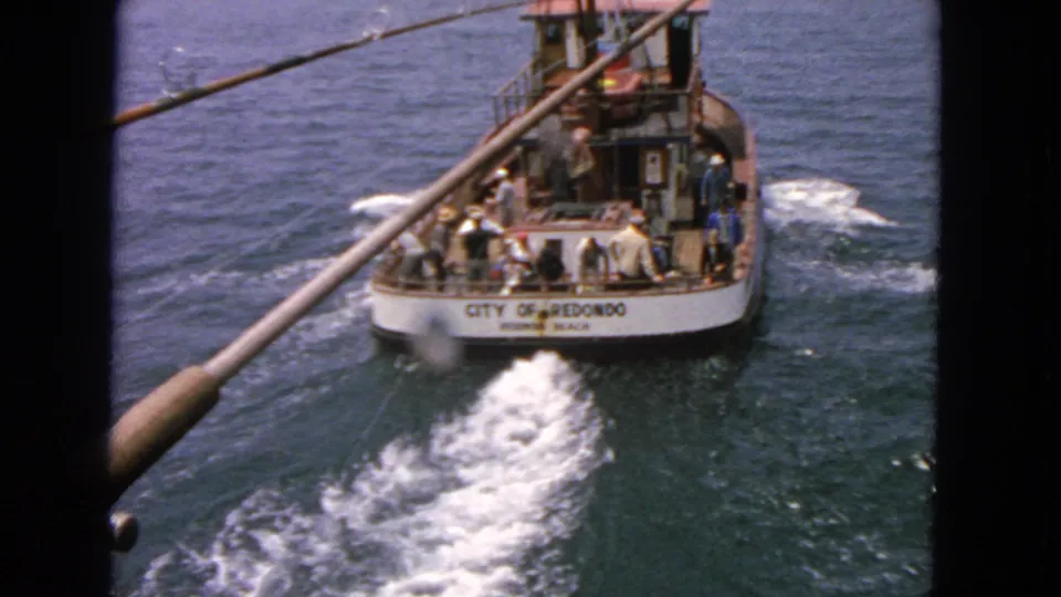 The City of Redondo boat is visible at sea in this 1963 home-movie frame, with passengers standing and sitting near the stern.