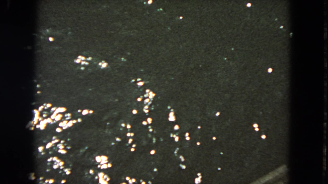 Dark rippling water with bright reflected highlights and black film borders.