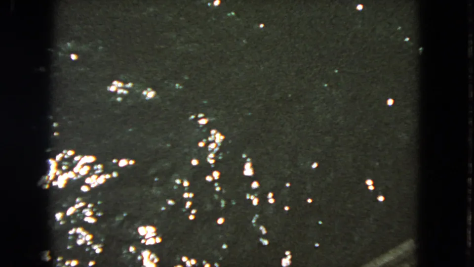 1963 San Francisco 8mm frame showing dark water, scattered reflections, and no clearly identifiable shoreline or people.
